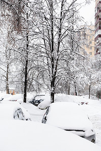 位于莫斯科市内下雪的住宅区公寓楼附近的雪覆盖了汽车图片