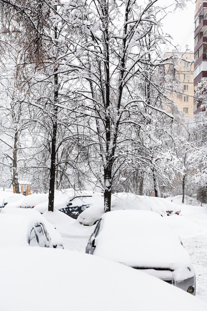 位于莫斯科市内下雪的住宅区公寓楼附近的雪覆盖了汽车图片