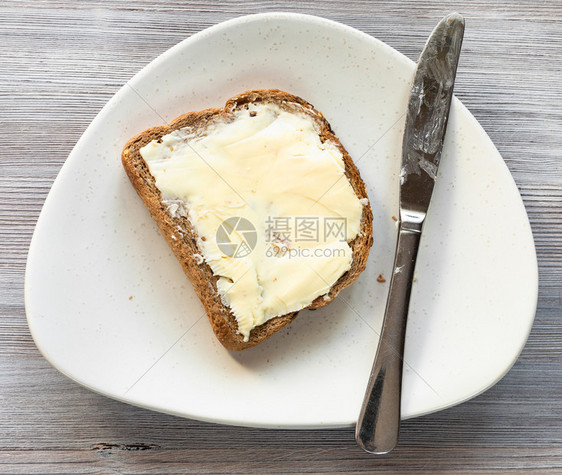 面包三明治的顶部视图灰色桌上白板有黄油和钢刀图片