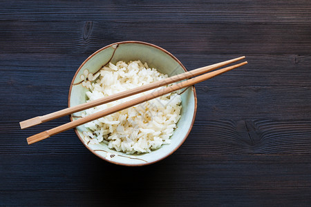 黑木板和复制空间的碗中煮饭上方的筷子顶部视图图片