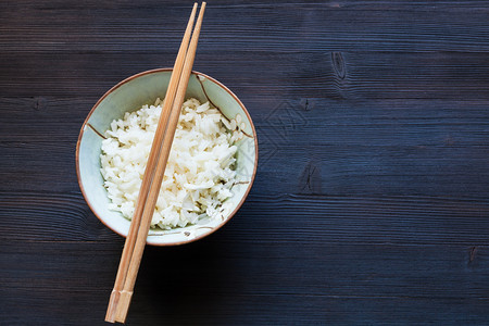 碗上方筷子的顶部视图黑木板上带复制空间的煮饭图片