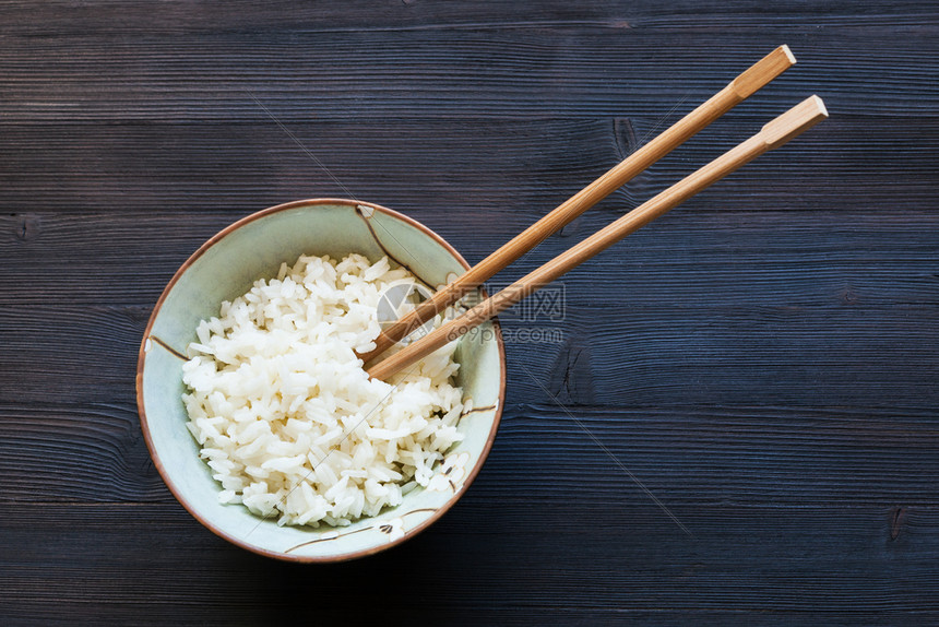 碗中的筷子和黑木板上煮饭的大米图片