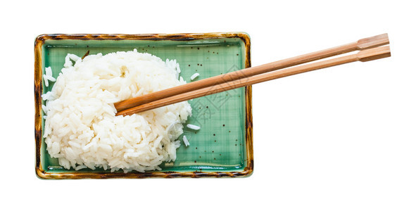 以白底隔离的绿色盘子上筷煮熟大米的顶部视图图片