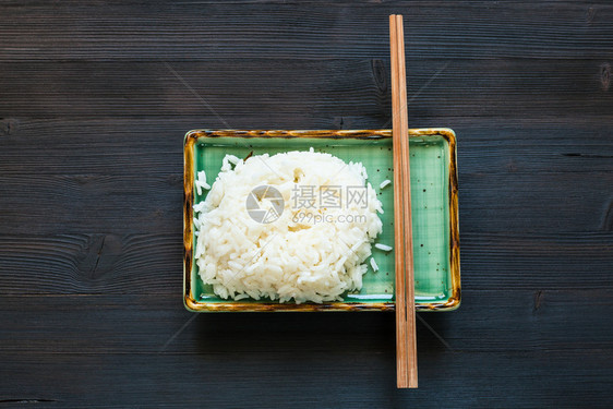 黑棕色桌绿板块上部分煮熟大米和筷子及复制空间的顶部视图图片