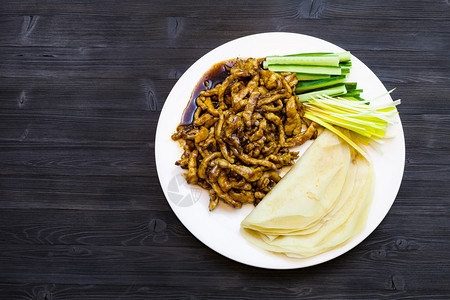 菜顶端白板面色在黄酱中煎炸肉片配有春洋葱新鲜黄瓜和煎饼鸡猪肉在黑木板上配有复印版面图片