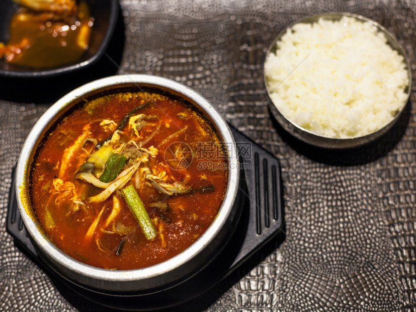 Korean烹饪当地餐馆金属碗中Yukgaejang热和辣汤包括牛肉鸡蛋蘑菇淀粉面扇菜ferns豆芽用煮饭供应的豆芽图片