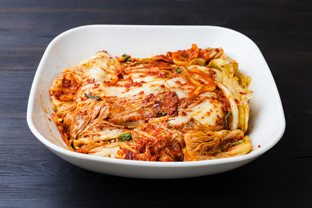 Korean烹饪kimchi黑棕色木板上白碗中的开胃菜spicenappa卷心菜图片