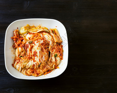 korean烹饪在Kimchi开胃菜Spicenappa卷心菜的上方白色碗黑棕木板上带有复制空间图片