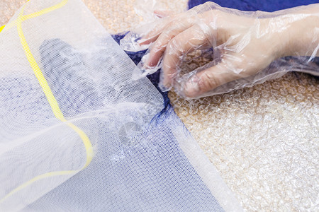 用湿感觉工艺蓝色梅里诺羊毛用手套制工艺人从剪裁模式的压纤维中除去塑料网格图片