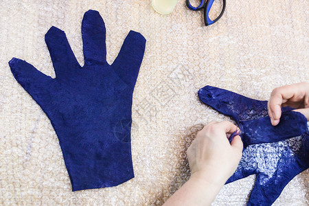 用湿感觉工艺蓝梅里诺羊毛用手套制工匠在切割型式上的手套背面图片
