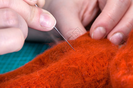 使用针感应工艺来修补羊毛手套的硕士班手工艺人用针感应合身的衣物图片