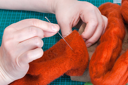 使用针头感觉程序修理羊毛手套的硕士班手工艺人修理用针头感觉手套图片