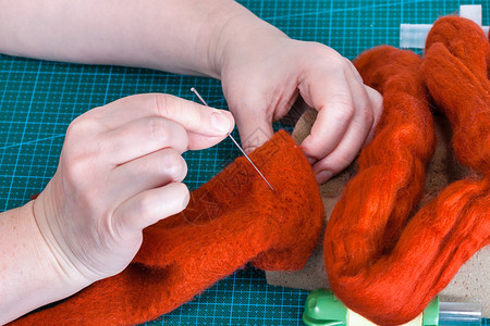 使用针触摸工艺来修补羊毛手套的硕士班手工艺人用针触摸感知来修补纤维图片