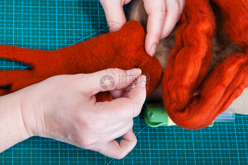 使用针触摸工艺修复羊毛手套的硕士班手工艺人用针触摸手套捆绑纤维的顶层视图图片
