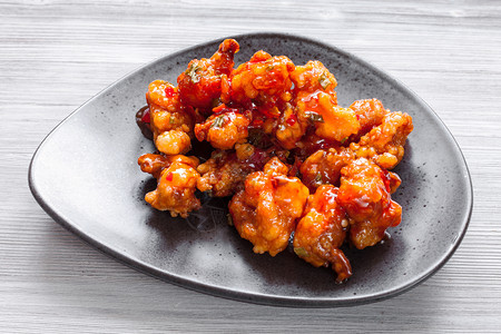 韩国中菜烤炒鸡肉蔬菜加甜酸酱黑盘上加紧贴上图片