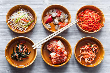Korean烹饪菜碗上的筷子和灰色桌上的各种边盘子Banchan或Panchan图片