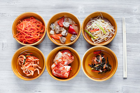 Korean烹饪灰色桌上有筷子的陶瓷碗中各种侧盘菜Banchan或Panchan的顶端视图图片