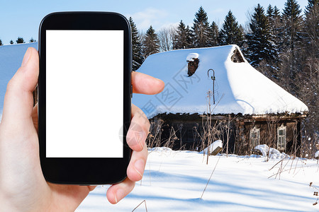 旅行概念俄罗斯莫伦克地区冬季在森林边缘的雪覆盖老农村房子旅游照片用智能手机拍摄屏幕上刻有空白广告位置的屏幕图片