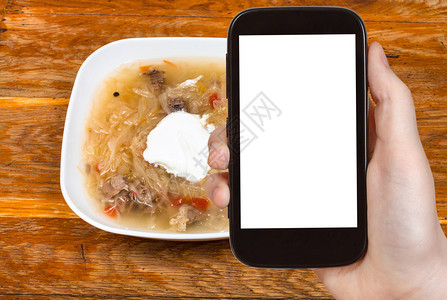 旅行概念俄罗斯菜汤和陶瓷碗中的酸苏和奶油的旅游照片智能手机上剪出带空白广告位置的屏幕图片