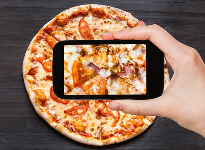 旅行概念用培根和番茄配方培根装满披萨的访客照片关闭智能手机图片