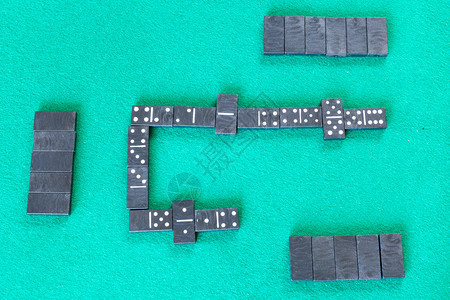 Dominoes棋盘游戏的顶端视图绿色烤桌上有黑瓷砖的牌棋盘游戏图片