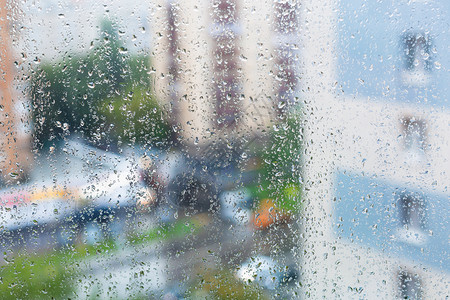 窗玻璃上的雨滴和秋天背景上的模糊城市街道图片
