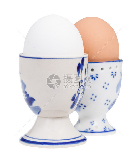 陶瓷鸡蛋杯中一对煮熟鸡蛋的面视图这些鸡蛋与白色背景隔绝蛋在前景之下图片