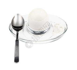 以白色背景孤立的玻璃鸡蛋杯中煮开的白和勺子图片