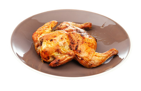将全扁鸡烤在棕色盘子上以白背景隔离图片