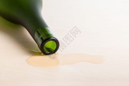 在木制桌上的溢出液体中白格纳克酒瓶边缘紧闭白格纳克酒瓶边缘在桌上的溢出液体中图片