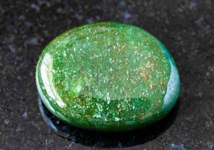 印度黑色花岗岩背景的绿色Aventurine宝石图片