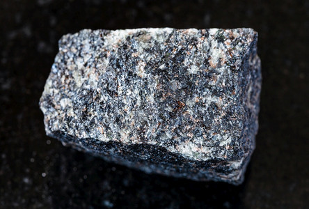 地质采集的天然矿物样本封存黑花岗岩背景上未污染的NephelineSyenite岩图片