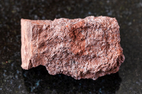 地质采集的天然矿物样本查封来自乌克兰的黑花岗岩背景上未排污的铝土岩图片