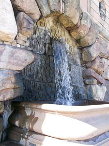 结石从建筑物墙外的旧泉源喷出瀑布老的图片