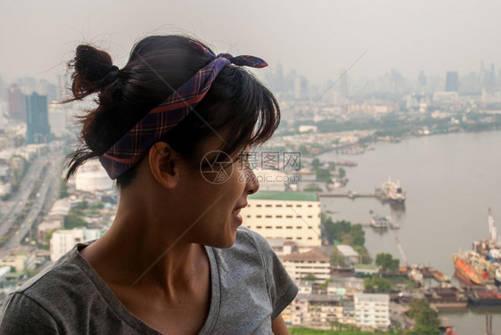 天空建造在曼谷ChaoPhraya河一望时女孩站在公寓阳台的上女士图片