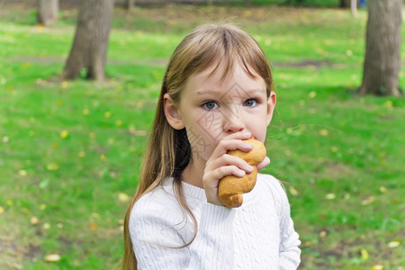 户外吃面包的小女孩图片