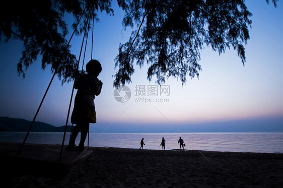 团体一个当地女孩在秋千上玩耍看着一群游客在泰国拉农高昌岛日落海滩上行走在泰国罗农高昌岛KohChangIsland步行摇摆图片