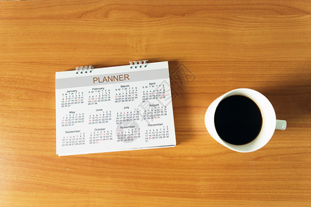 笔记一种商务日历旅行规划用木制桌上的一杯咖啡来作记号后加注图片