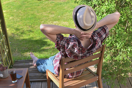 年轻人看到坐在椅子上着花园里放松露台阳帽子图片