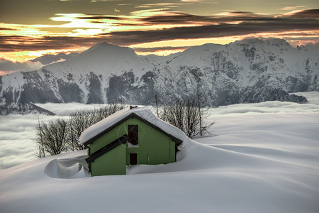 放松阿尔卑斯山神奇日落时雪下高山小屋图片