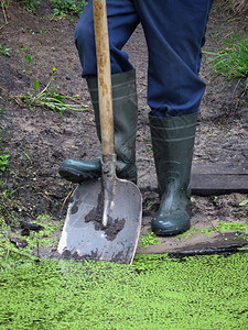 贴近一个用橡胶靴子铲挖池塘的人工具开机一种背景图片