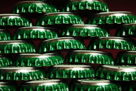 绿色啤酒帽堆积的绿色啤酒盖为背景而关闭好用过的圆形刮图片