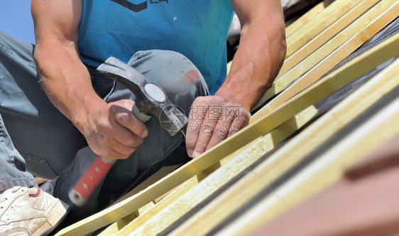 锤子建造装修紧贴着一个工人的手钉着一堆垃圾以唤醒房子的屋顶图片