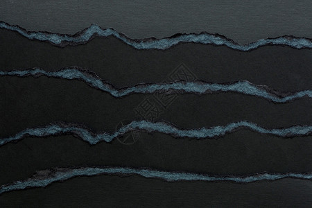海浪衣衫褴褛破旧背景和几层黑纸板的纹理上面有撕裂边缘图片