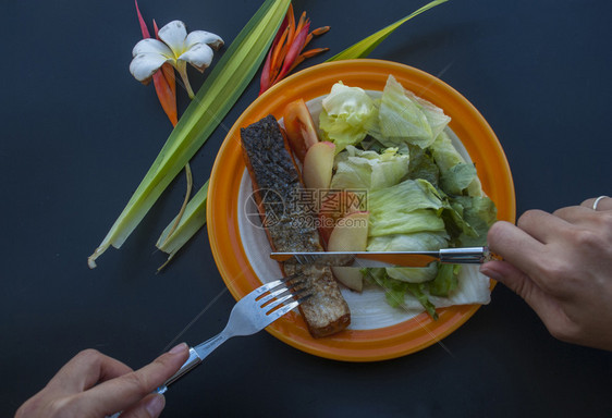 黑桌上有蔬菜沙拉的牛排配桌子花三文鱼图片