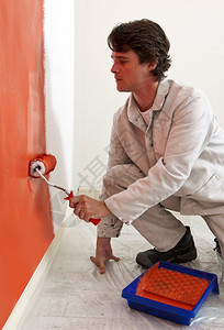 跪着画墙橙色和涂漆滚筒单身的改进背景图片