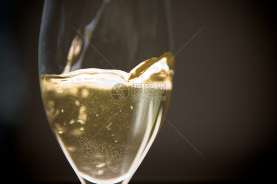 喝浇注酒精倒在瓶子的玻璃杯上图片
