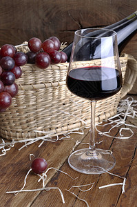 木制的葡萄篮子上前的酒杯以生锈木制背景用瓶装酒供应葡萄喝水果图片