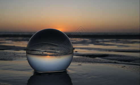 领域地平线晚上在海滩的日落捕捉在玻璃晶体球中图片