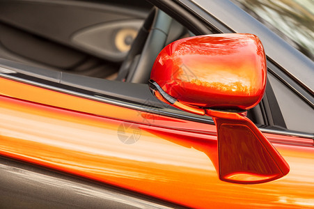 在一辆明亮橙色豪华运动车上关闭了一面驾照镜奢华明亮的反思背景图片